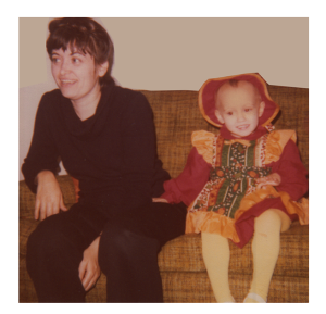 Lrl with her daughter, dressed in a pinafore over a red dress with matching hat.